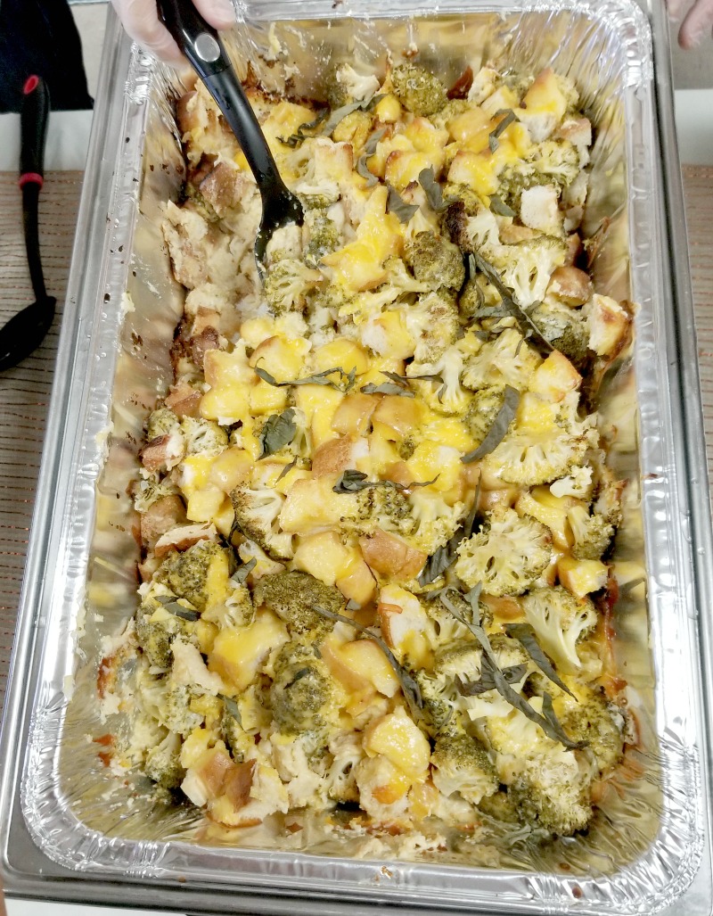 Top down view of the finished cheesy broccoli casserole for a crowd with a serving spoon