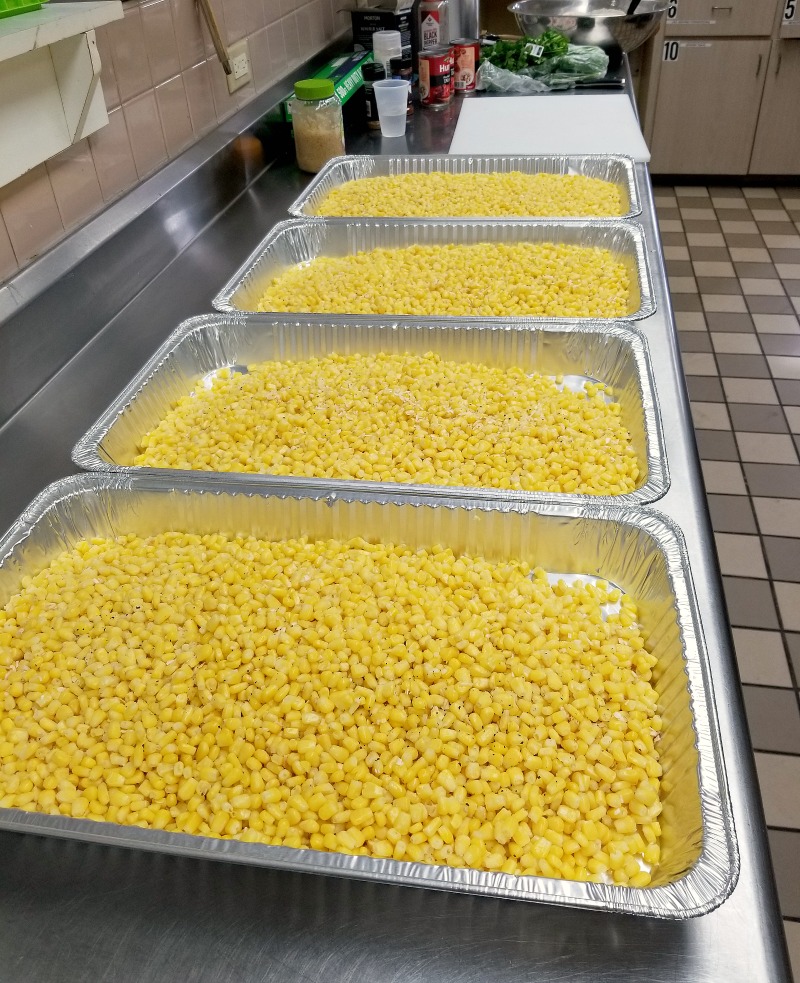 4 hotels pans, each with corn showing the amount of food for vegetable side dishes for a crowd