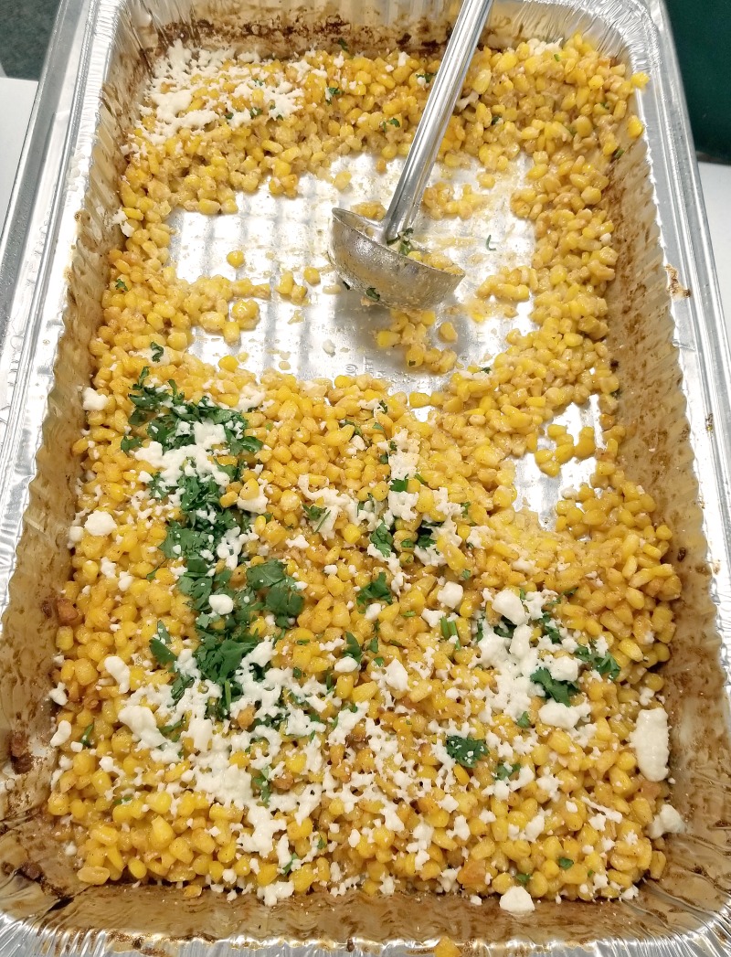 finished Mexican Street Corn in a hotel pan with a ladle for serving