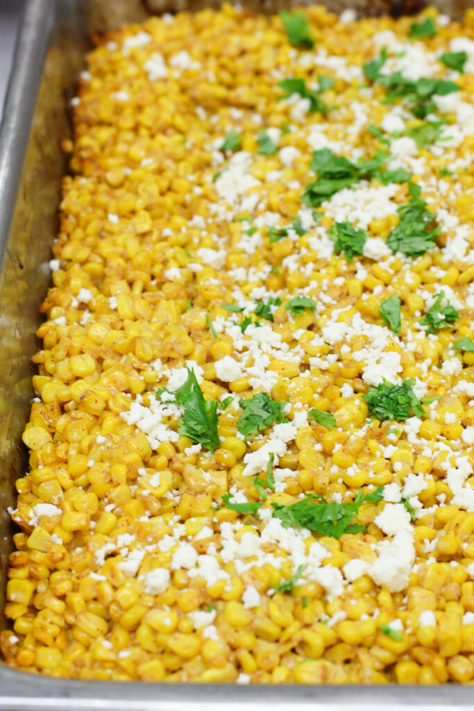 prepared Mexican street corn casserole in hotel pan topped with cheese and herb