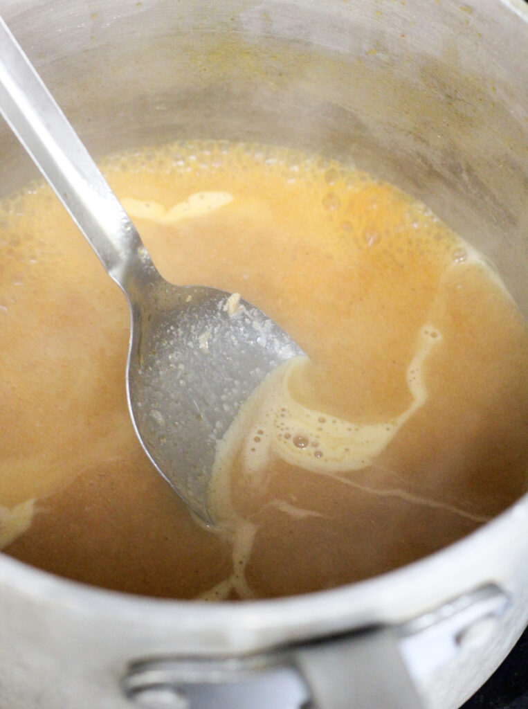 metal spoon in saucepan with gravy