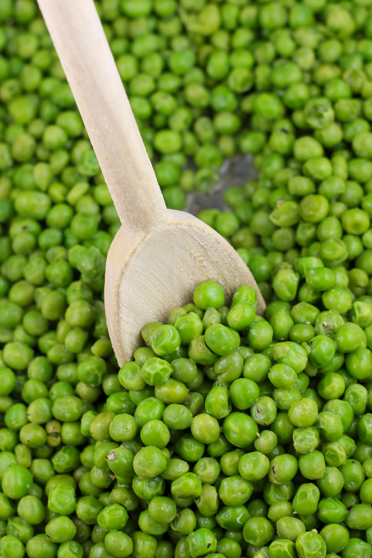 wood spoon inserted into cooked peas