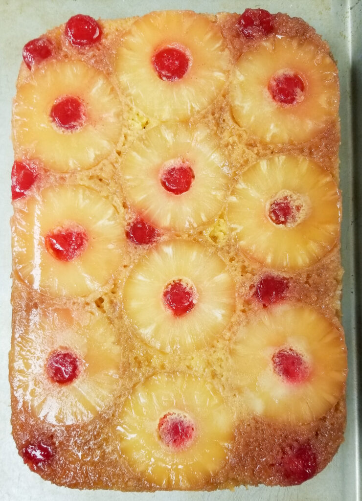 whole pineapple upside down cake without nuts, removed from bake dish, on bake dish