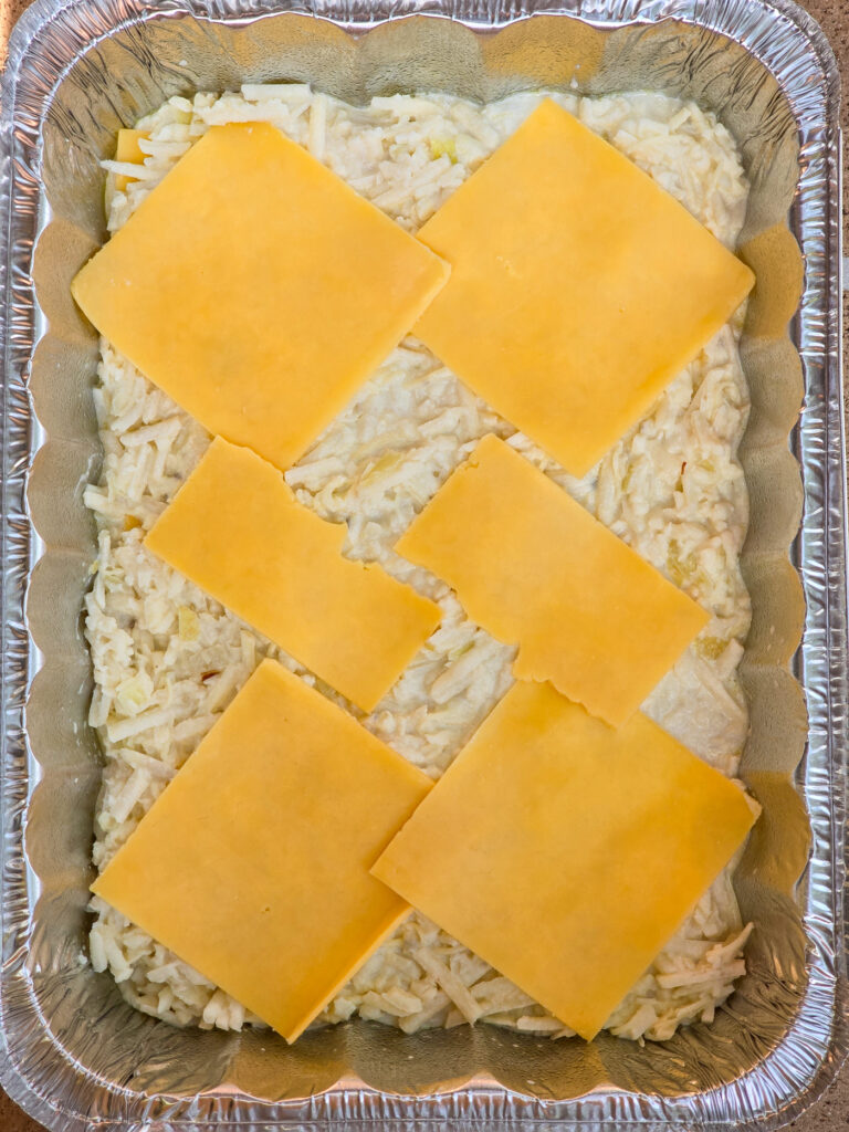 potato-cream mixture in pan topped with slices of Gouda cheese