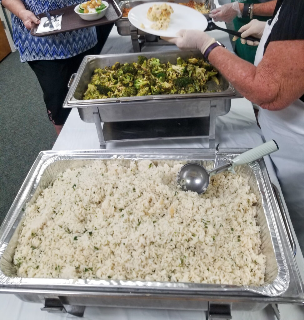 buffet line with hotel pan of baked rice in the foreground