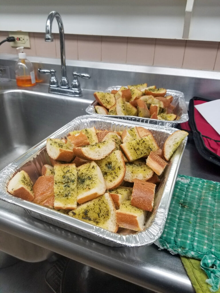 portions of prepared garlic bread in hotel half pans