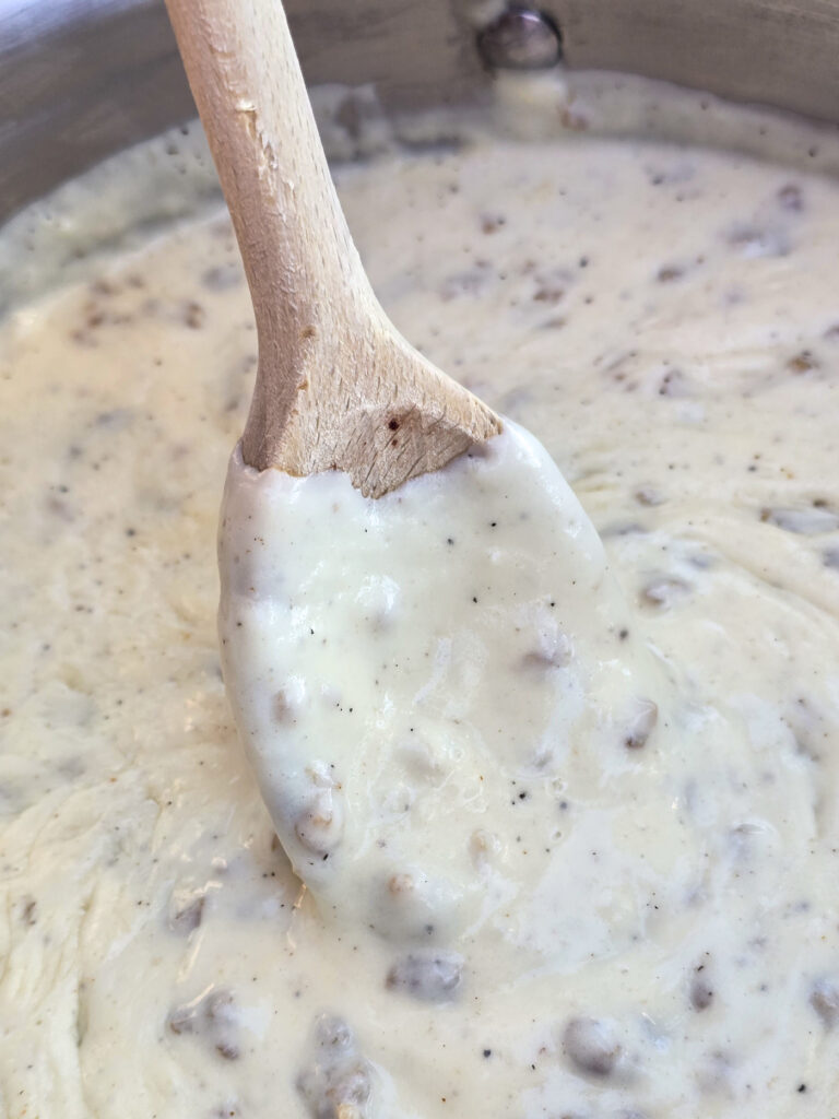 wood spoon in prepared sausage gravy in pot