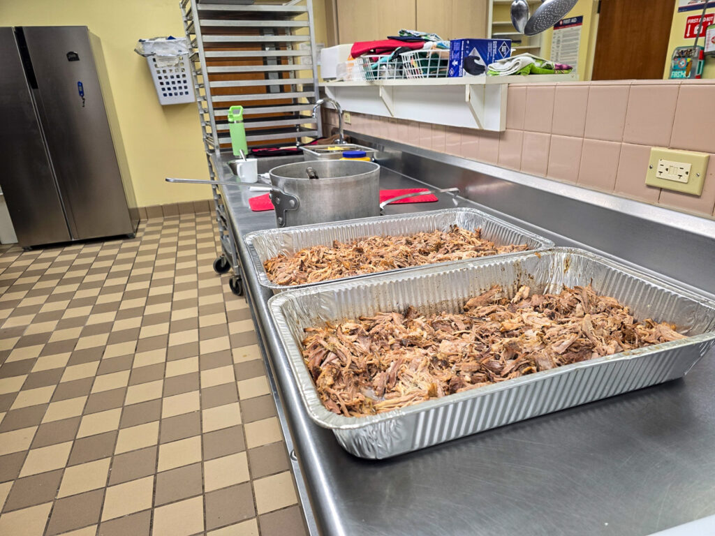 large kitchen with 2 aluminum pans of pulled pork on counter