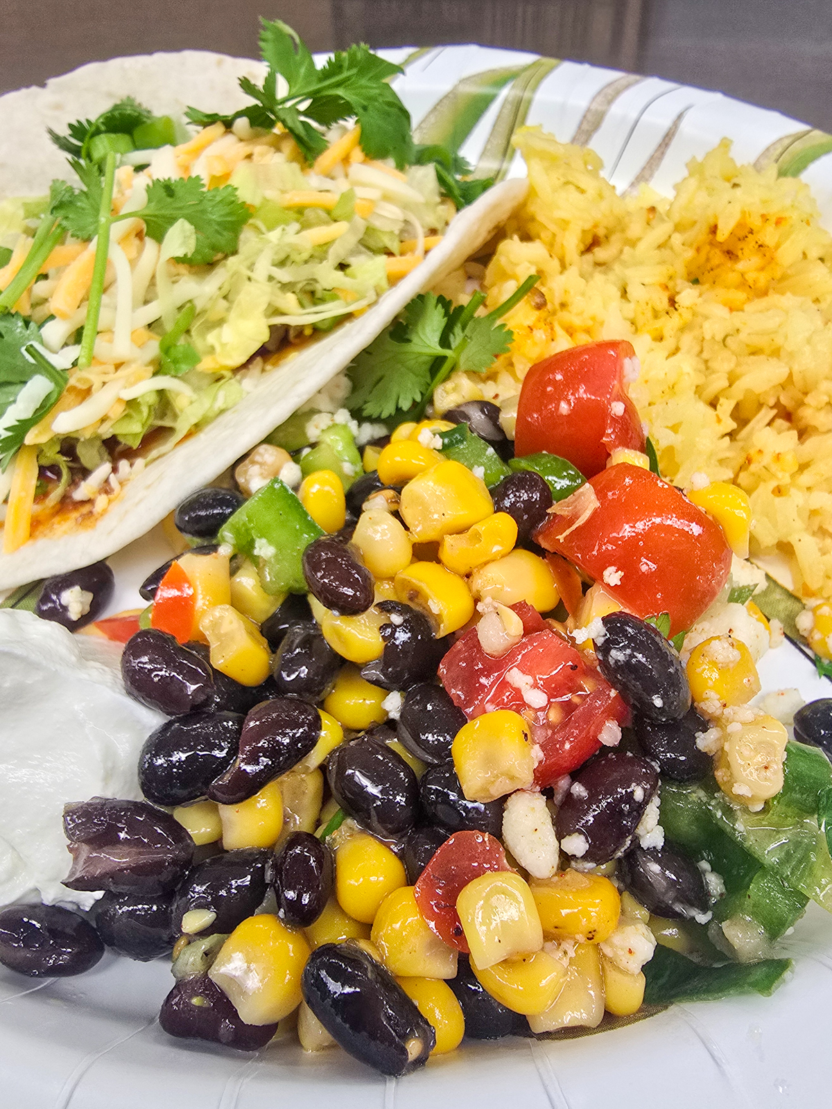 serving of black bean and corn salad on plate with a taco and yellow rice