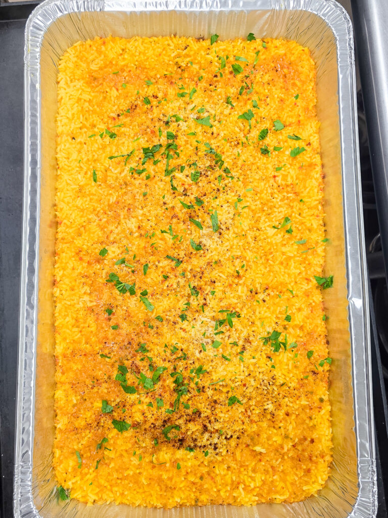 A large commercial hotel pan filled with perfectly cooked, fluffy oven-baked yellow rice fresh from the oven.